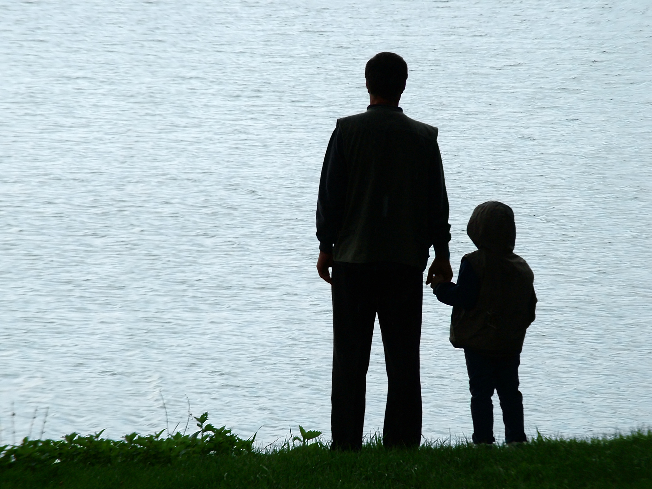 Man and child silhouette at lakeside in evening